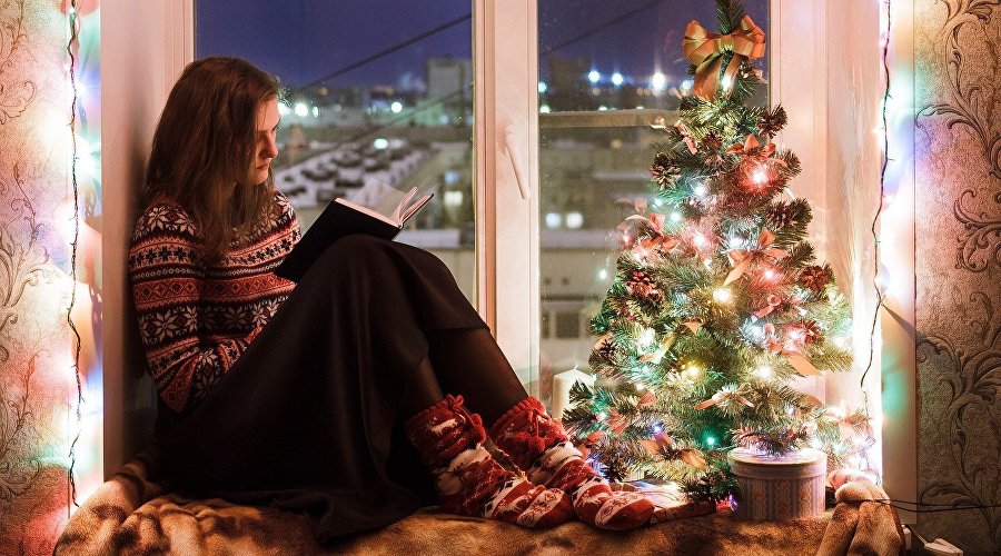 Девушка читает книгу у новогодней ёлки