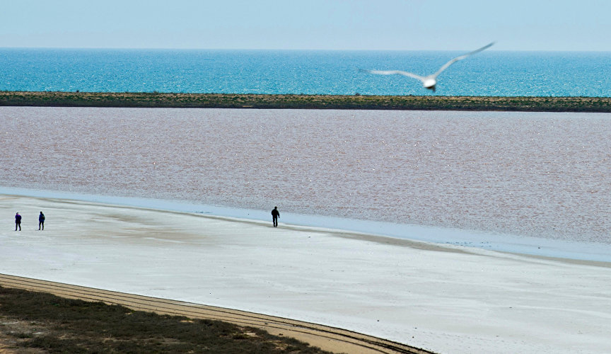 Яркий водоём контрастирует с белоснежным побережьем и синью Черного моря, отделённого узкой песчано-ракушечной полоской – Кояшской пересыпью