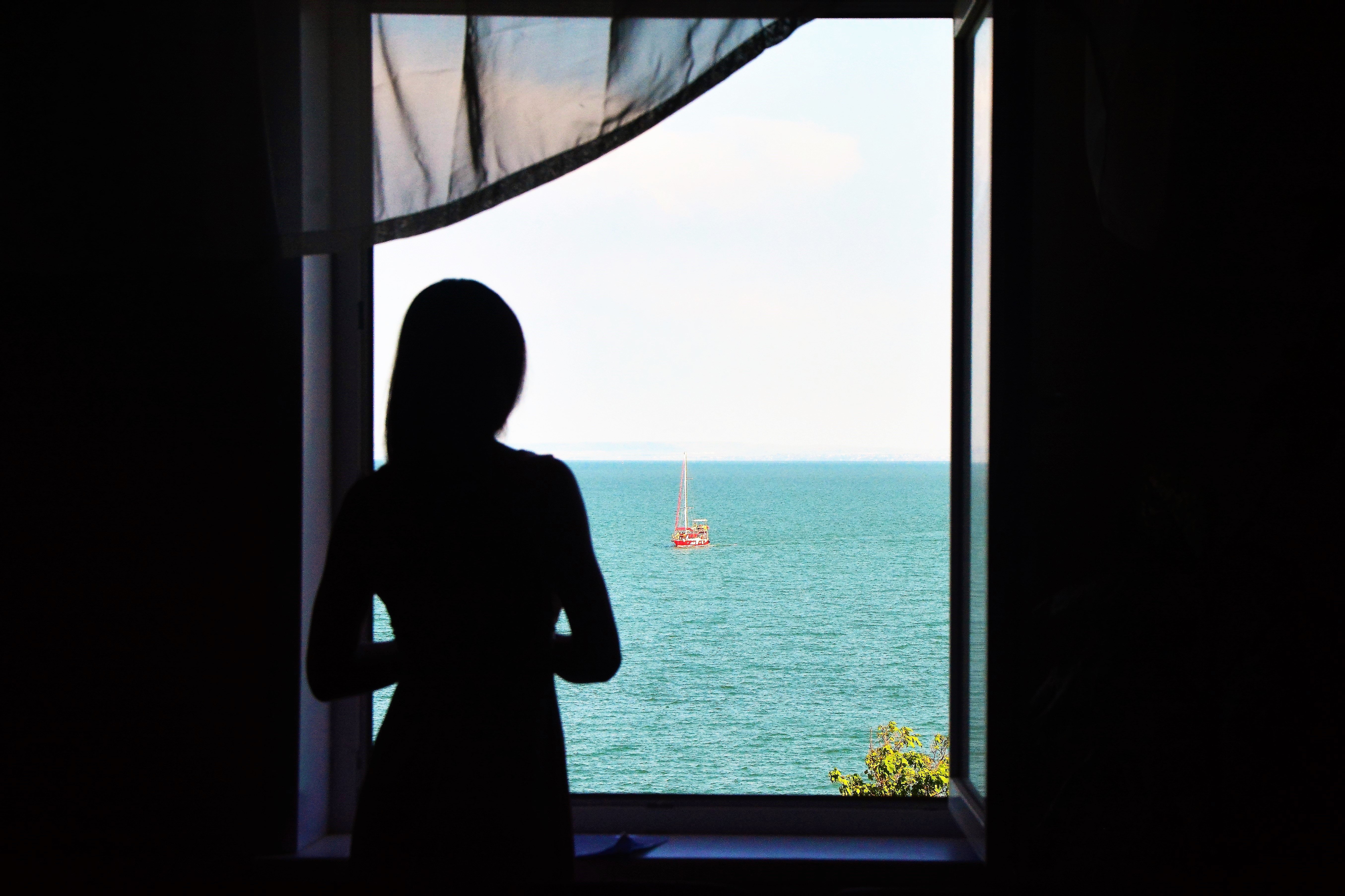 Девушка смотрит на море в окно в Керчи