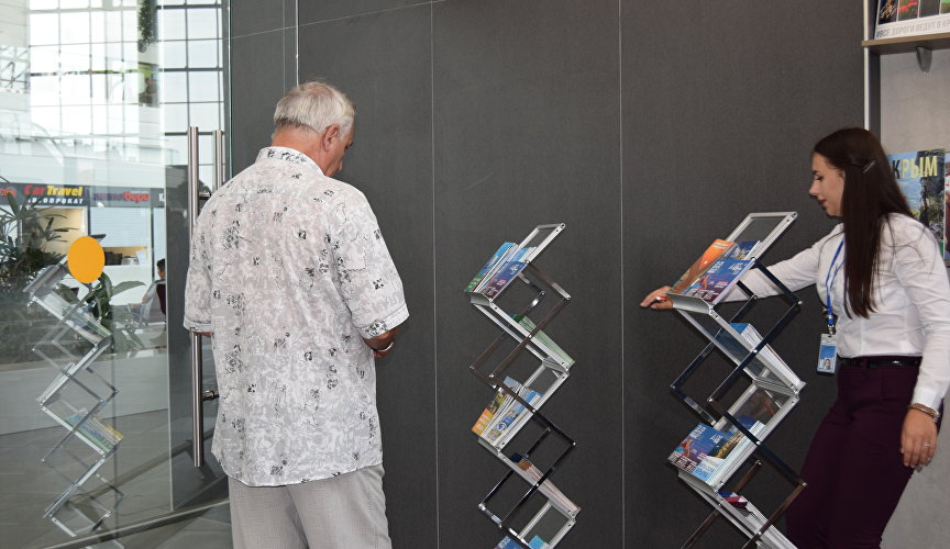 Мужчина изучает брошюры туристско-информационного центра в аэропорту Симферополь